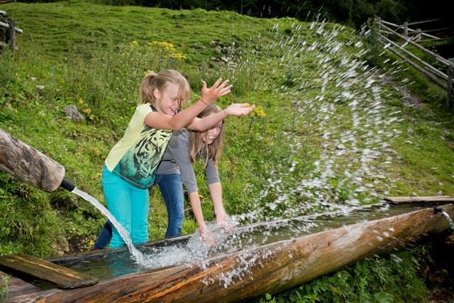 Kinder plantschen am Brunnentrog bei Langfeldhütte