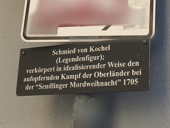 Eine Zusatztafel, die über den Schmied von Kochel informiert