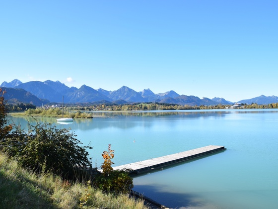 Forggensee mit Steg und Berge im Hintergrund