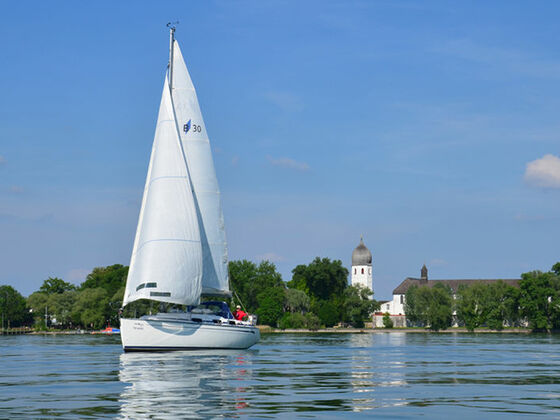 Segelschiff am Chiemsee mit Fraueninsel im Hintergrund.