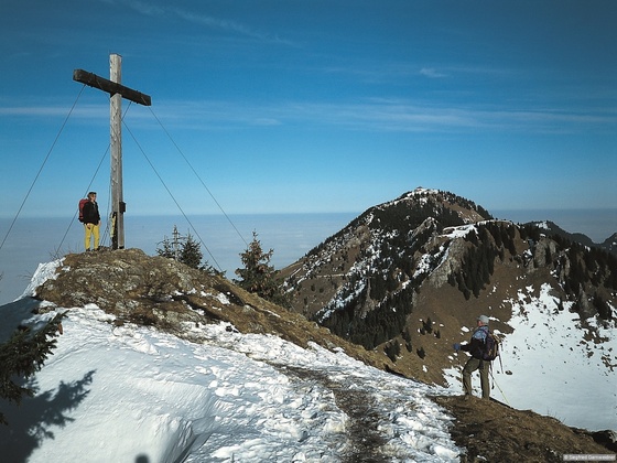 Wir kommen in den Wald hinein und am Wanderweg, streckenweise etwas steil, auf den dritten Gipfel dieser Tour, das Feichteck hinauf. Rechts auf dem Foto die Hochries. Beim Rückweg vom Feichteck müssen wir erst einmal in den Sattel vor dem Karkopf zur