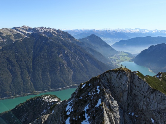 Das Gipfelkreuz der Seebergspitze, dahinter der türkisblaue Achensee.