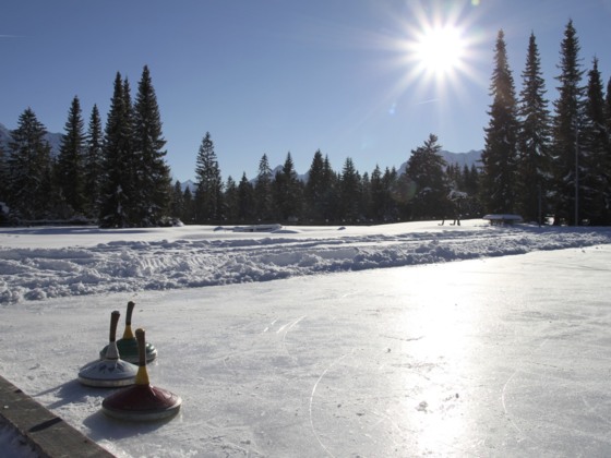 Natur-Eisplatz in Wallgau im Winter mit Sonnenschein