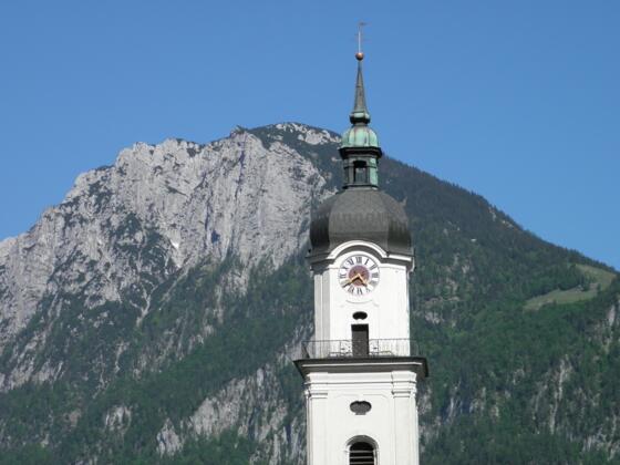 Die Pfarrkirche Heilig Kreuz, dahinter der Zahme Kaiser