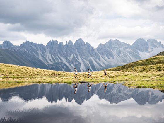 Drei Trailrunner:innen laufen vor dem Salfeiner See