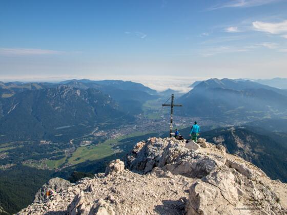 Das Gipfelkreuz der Alpspitze mit Garmisch-Partenkirchen im Talgrund