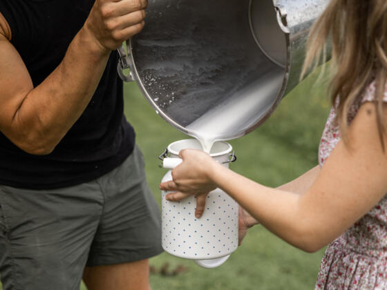 zwei Personen beim Milch umfüllen - Symbolbild