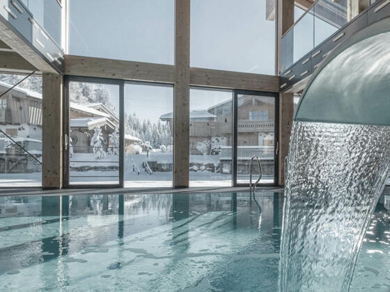 INNs HOLZ Chaletdorf | Vitaloase mit Indoorpool und Blick auf den INNs HOLZ See und das verschneite Chaletdorf