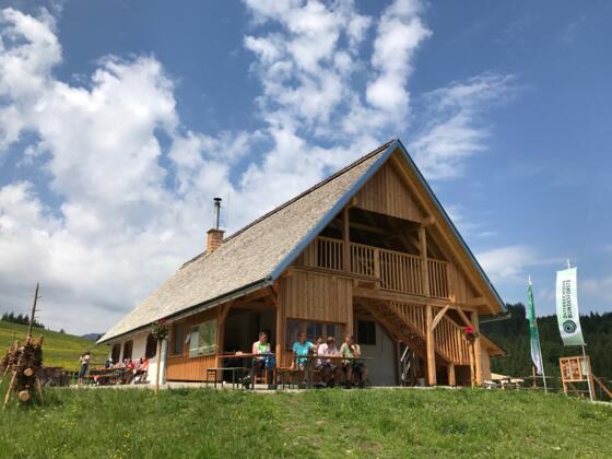 moderner Hütten-Zubau aus Holz, Besucher sitzen vor der Hütte