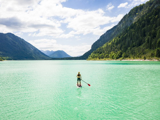 Fjordartiger Sylvensteinsee mit SUP-Paddler