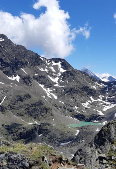 Der Grastalsee, eingebettet zwischen Breiten Grieskogel und Hörndle, wird sichtbar.