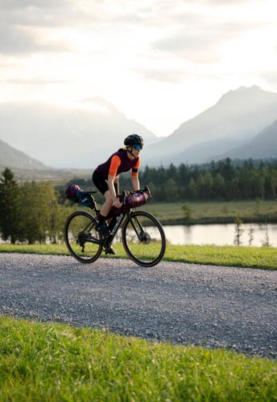 Eine Gravelbikerin fährt auf einem Feldweg entlang des Geroldsees in der Zugspitz Region.