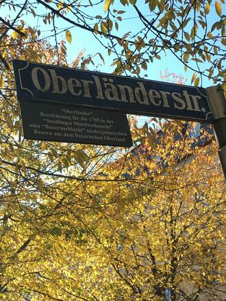Das Straßenschild der Oberländerstraße in München mit Zusatztafel