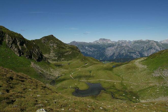Hier sieht man, woher der Herzsee seinen Namen hat. Weiter hinten im Bild sieht man den Skitunnel und das Lechquellengebirge mit der roten Wand