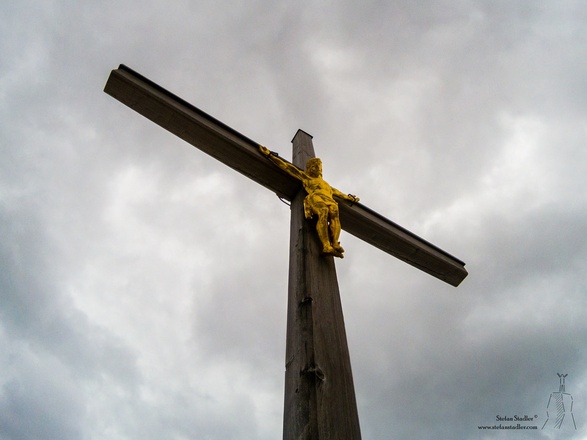 Das schöne Gipfelkreuz auf der Wasserwand unter dunklen Wolken
