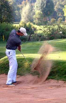 Golfer beim Schlag aus dem Bunker auf der Golfanlage Gut Ising.