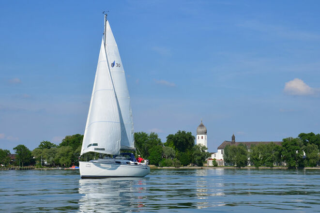 Segelschiff am Chiemsee mit Fraueninsel im Hintergrund.