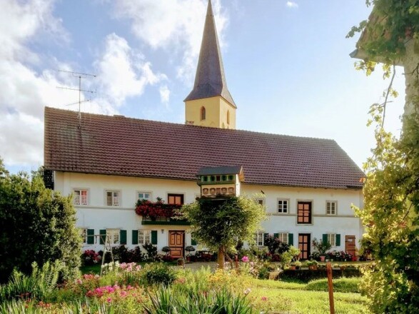 Historischer Salzmeier Hof in Wang mit der Filialkirche Sankt Johannes der Täufer im Hintergrund