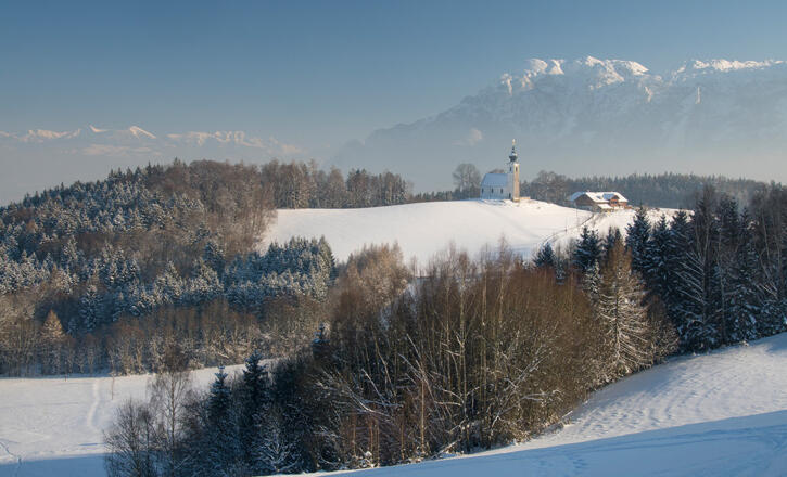 Kirche und Wirtshaus vor Bergkulissee: Johannishögl in Piding im Winter