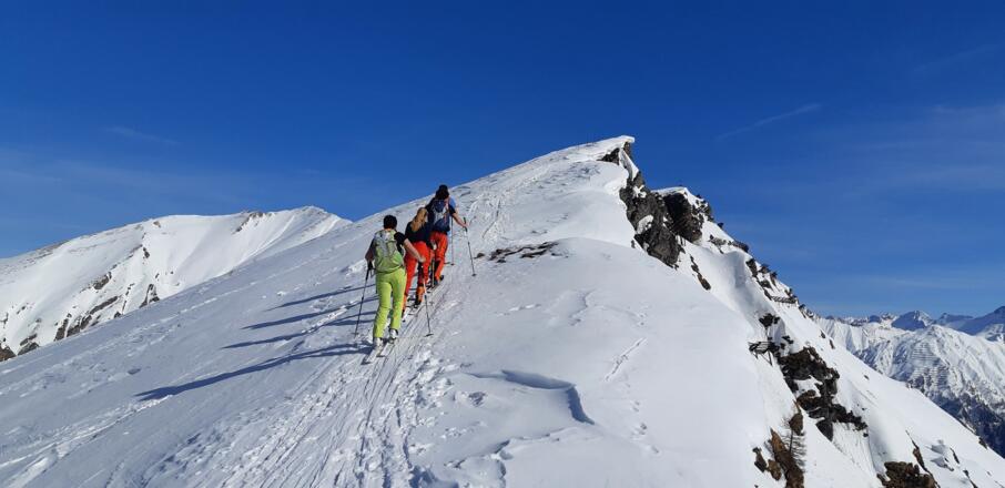 Der Gratverlauf weist den Weg, erstmals ist das Gipfelkreuz in Sicht. Achtung: Wechten!