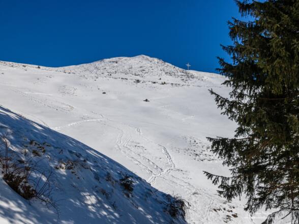 Das Gipfelkreuz des Wandberg erscheint oben am Horizont.