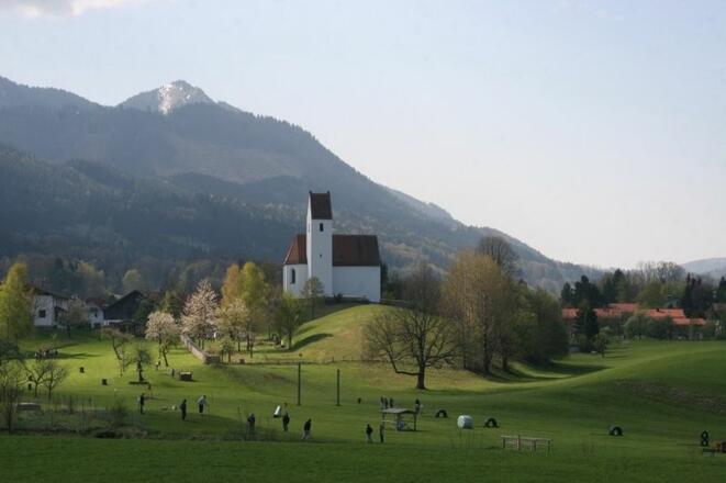 Das Bild zeigt die herrliche Lage des Bauerngolfplatzes mit Blick auf die Kirche und die umliegenden Berge.