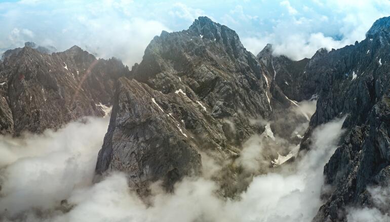 Das Totenkirchl umgeben von Wolken und schroffen Felswänden.