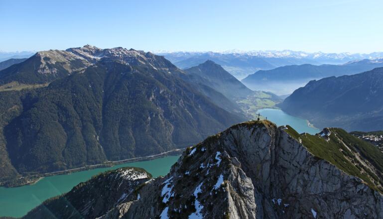 Das Gipfelkreuz der Seebergspitze, dahinter der türkisblaue Achensee.