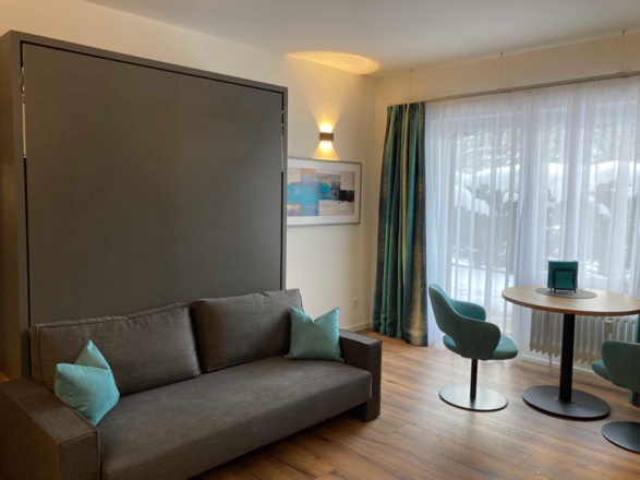 gemütliches Sofa (mit einem Handgriff zum Bett (160 x 200) umbaubar) mit kleinem Esstisch und Blick auf die Süd - West Terrasse vom Sofa bzw. Esstisch.