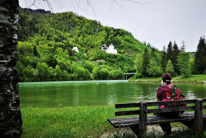 Wanderin rastet am Klauser Stausee mit Blick auf Schloss Klaus