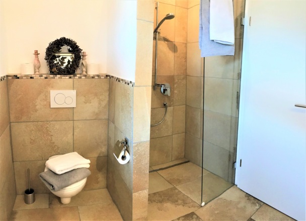Für das Komfort sorgt die bodengleiche Dusche mit integrierter Bodenheizung, Föhn und Fenster.