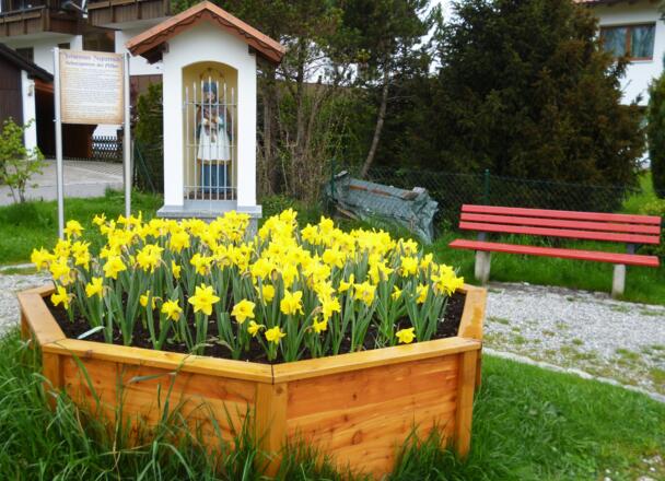 Bildstock mit Bänken und Blumen an der Uferpromenade des Oberen Lechsees in Lechbruck.