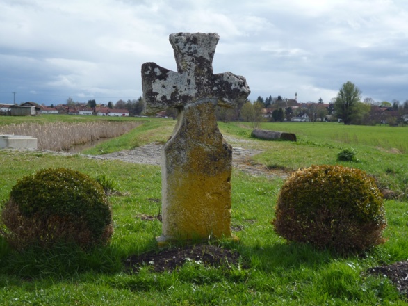 Am Straßenrand steht direkt vor dem Regenwasserrückhaltebecken ein Steinkreuz (Sühnekreuz) aus Tuffstein.