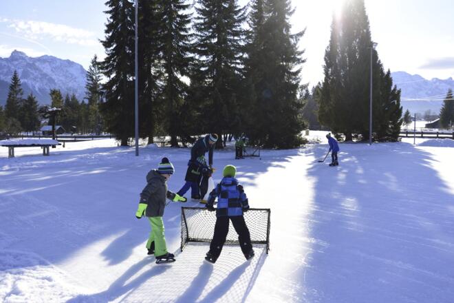 Schlittschuhlaufen und Eishockey spielen auf dem Natur-Eisplatz in Krün Winter