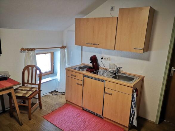 Die Küchenzeile mit 2 Herdplatten, Kühlschrank und Spüle