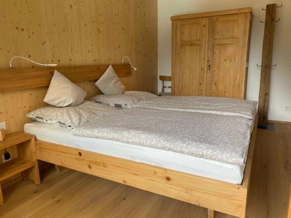 Das Balkonzimmer mit Doppelbett 180 X 200 und einem rustikalen Kleiderschrank, beides aus alter Fichte