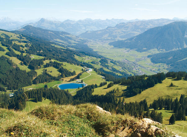 Von der Hohen Salve blicken wir auf Hochbrixen mit dem Filzalmsee. Im Hintergrund das Kitzbüheler Horn.