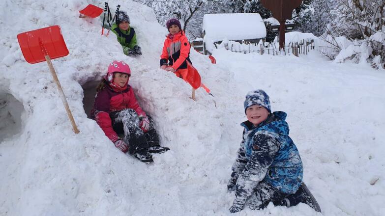 Kinder spielen im Winter vor dem Haus