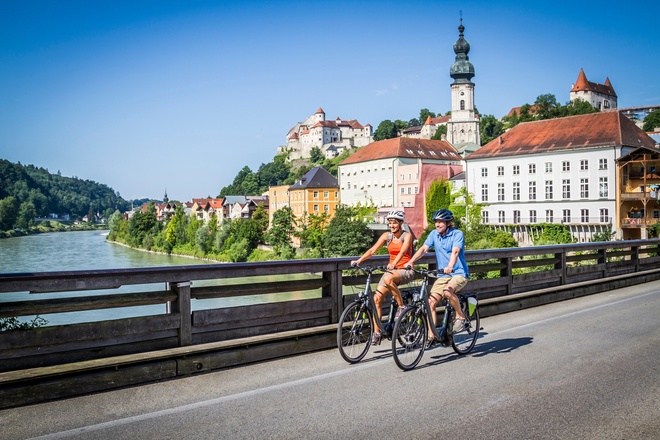 Radfahrer mit Burghauser Altstadt und Burg im Hintergrund