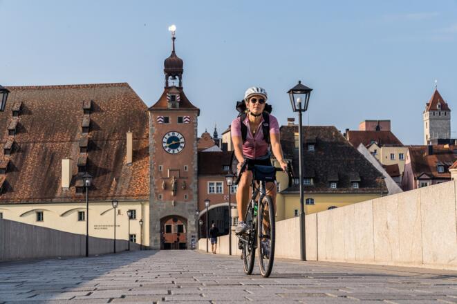 Radfahrerin auf der Steinernen Brücke in der UNESCO Welterbestadt Regensburg - hier endet die Niederbayerntour