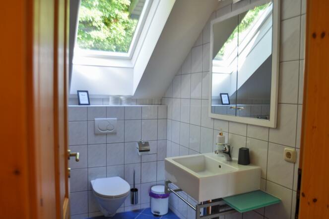 Wohnraum mit Kachelofen und Aufgang Obergeschoss