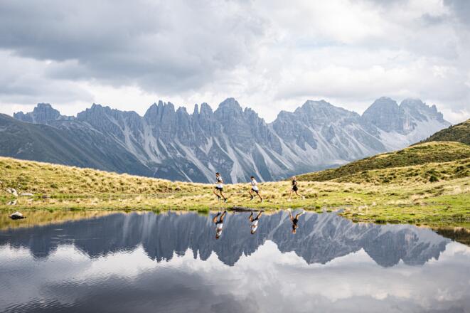 Drei Trailrunner:innen laufen vor dem Salfeiner See
