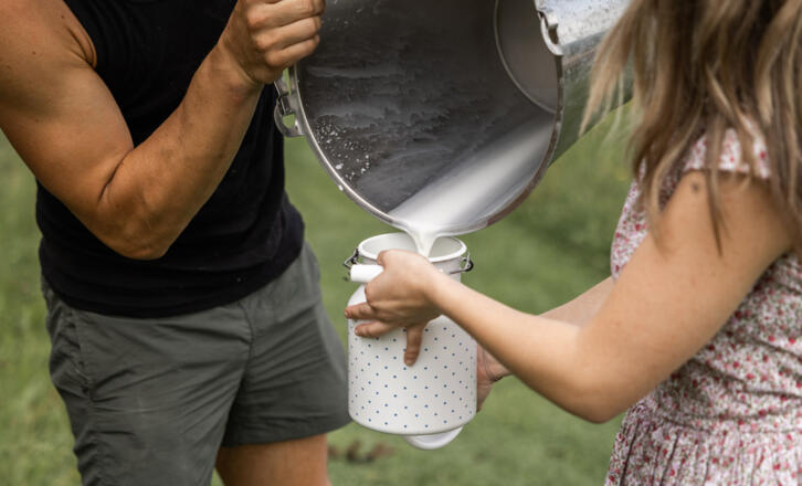 zwei Personen beim Milch umfüllen - Symbolbild