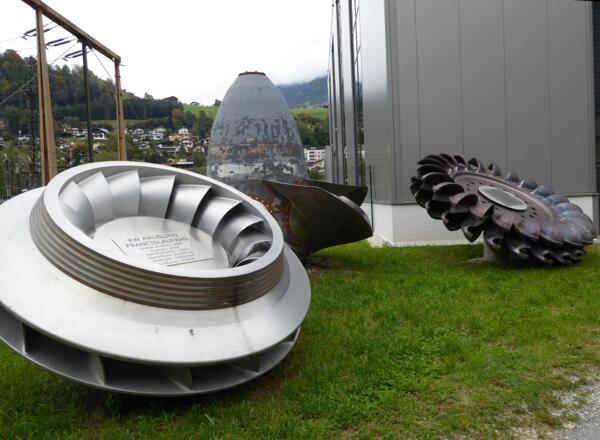 Vor dem Krafthaus sind verschiedene Turbinen-Typen ausgestellt: links Francis, rechts Pelton, mittig Kaplan.