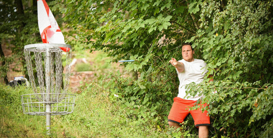 Ein Mann spielt Discgolfkorb