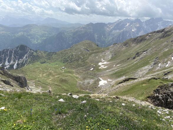 Tiefblick vom Gipfel hinunter über das weitläufige Becken zum Padasterjochhaus und hinüber zu den Obernberger Bergen mit den Tribulaunen.