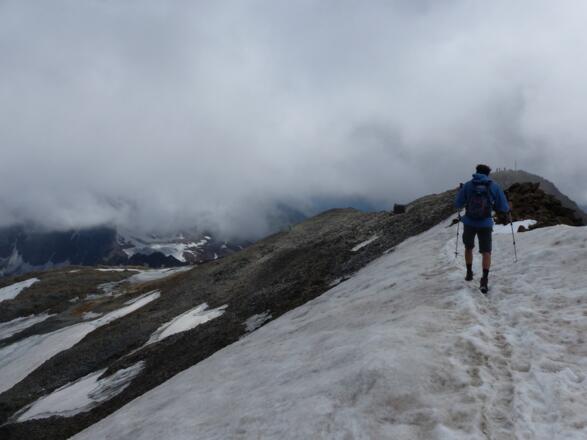 Über Firnfelder und Schutt geht es nun sanft zum Signalgipfel. Erkennbar ist auch die verfallene Zollhütte.