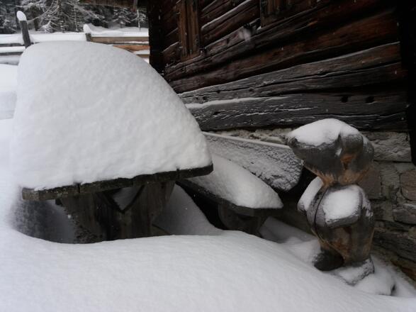 Tisch und Bank neben der geschnitzten Figur laden im Sommer zur Rast ein.