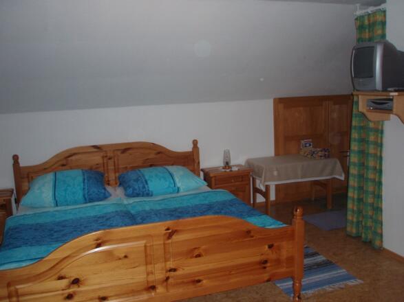 Doppelbett mit Fernseher und kleine Sitzecke
