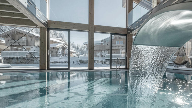 INNs HOLZ Chaletdorf | Vitaloase mit Indoorpool und Blick auf den INNs HOLZ See und das verschneite Chaletdorf